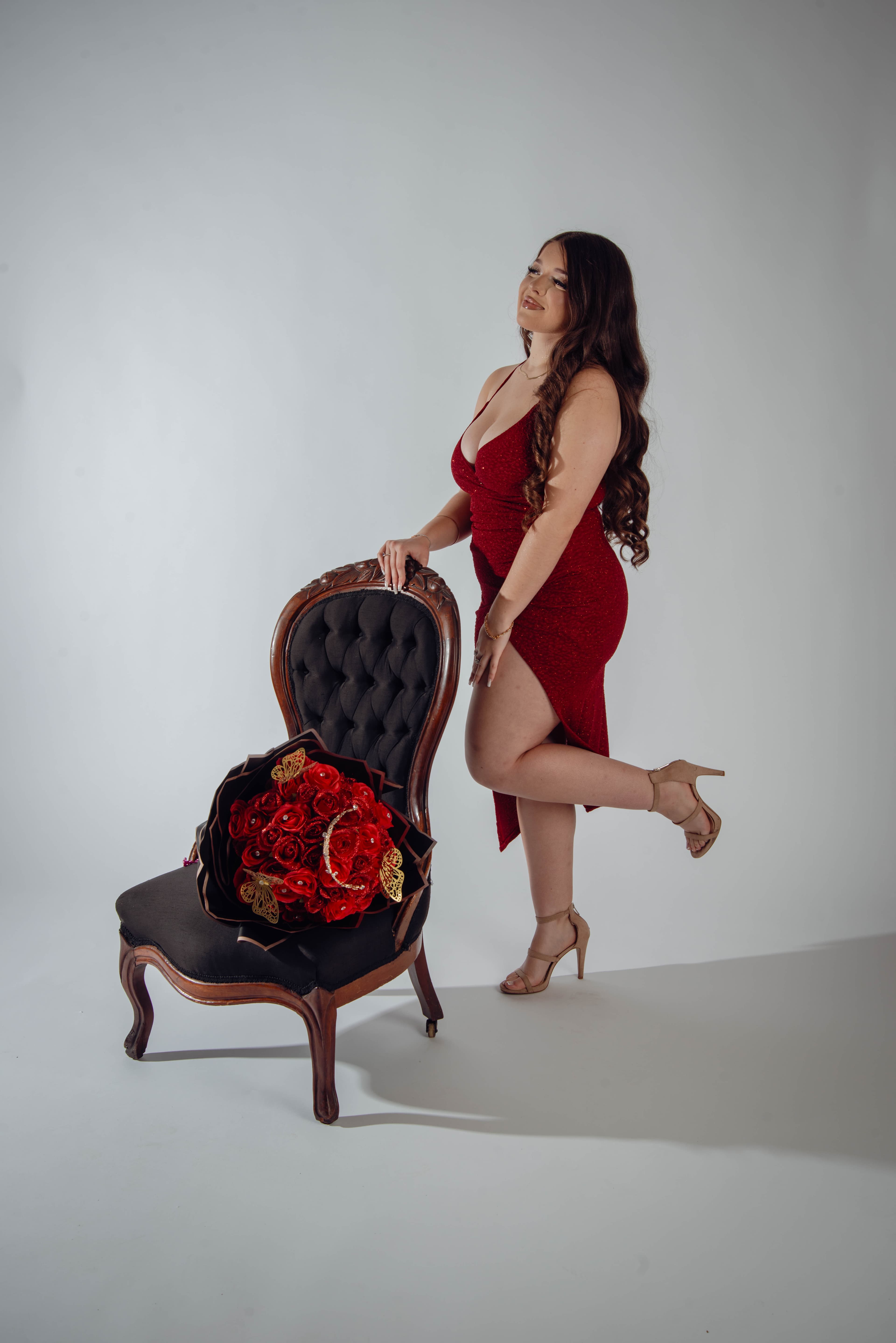 Birthday portrait posing with vintage chair and red roses in red dress