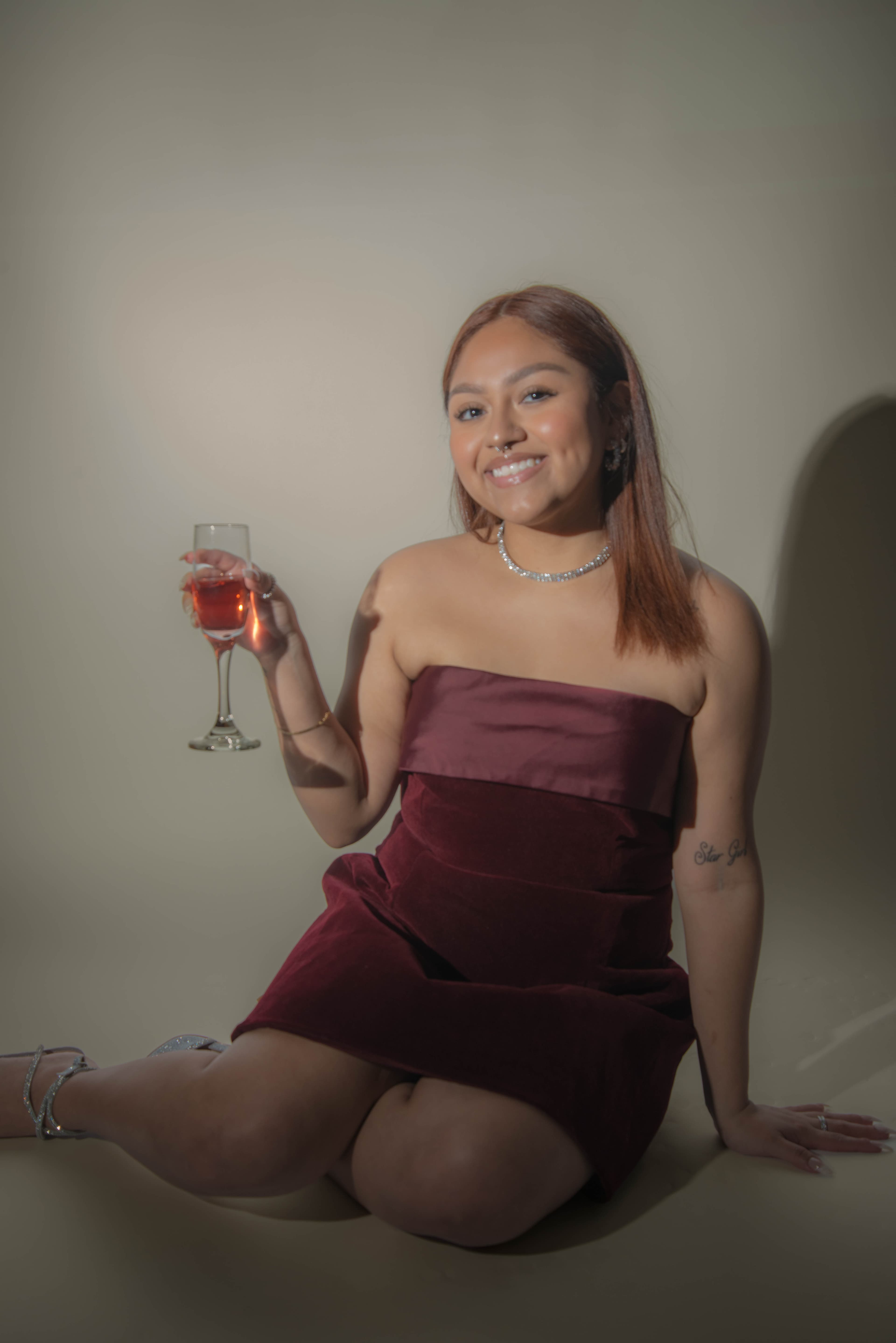 Birthday portrait seated holding champagne flute in burgundy dress